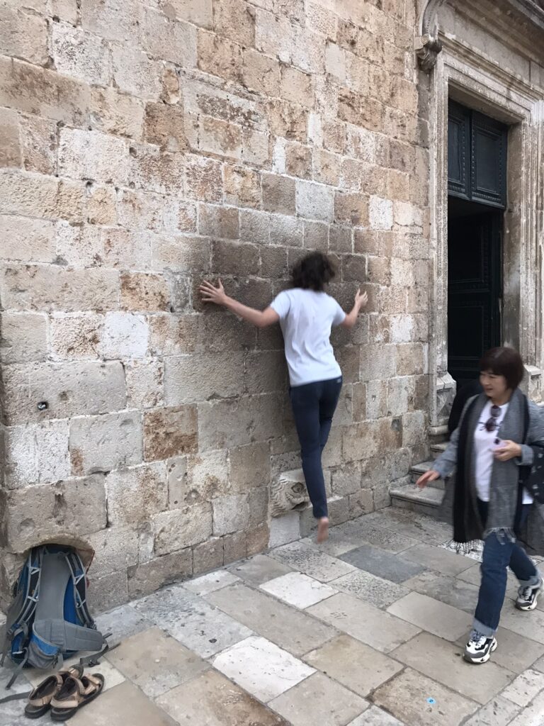 A man attempting to balance on a gargoyle in Dubrovnik