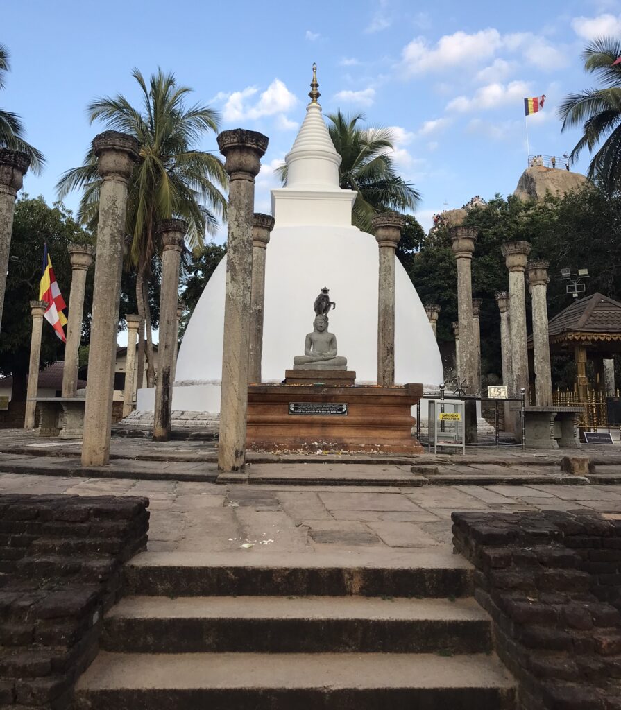 A monkey sitting on a Buddha statue in Mihintale